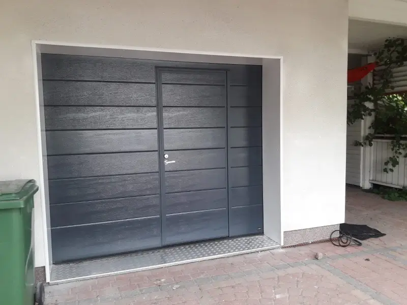 Autotallin ovi käyntiovella asennettuna Kotkassa — peltipielet ja turkkipeltikynnys — JK-Ovet