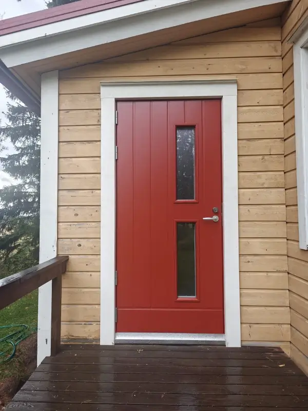 Punainen ulko-ovi puupielillä Lyöttilässä